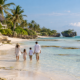 Family walking in shallow water on a beach in Watamu, Kenya