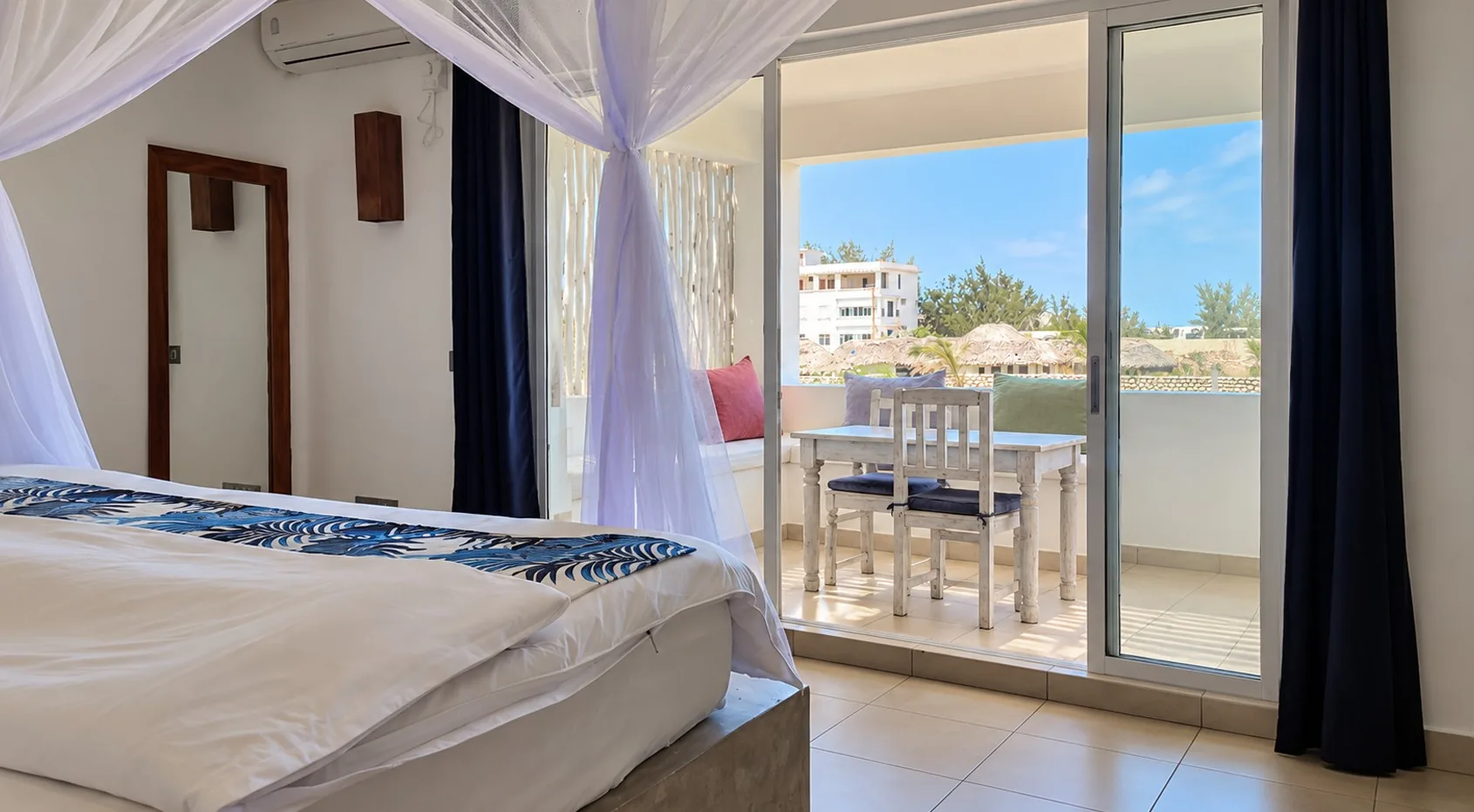 Family Suite bedroom with canopy bed and balcony at Visiwa Beach Resort, Watamu