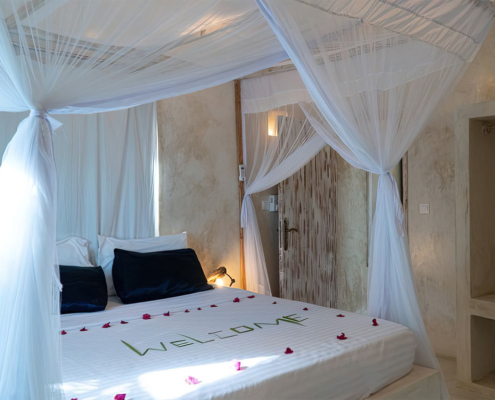 Apartment bedroom with canopy bed and mosquito net at Visiwa Beach Resort, Watamu
